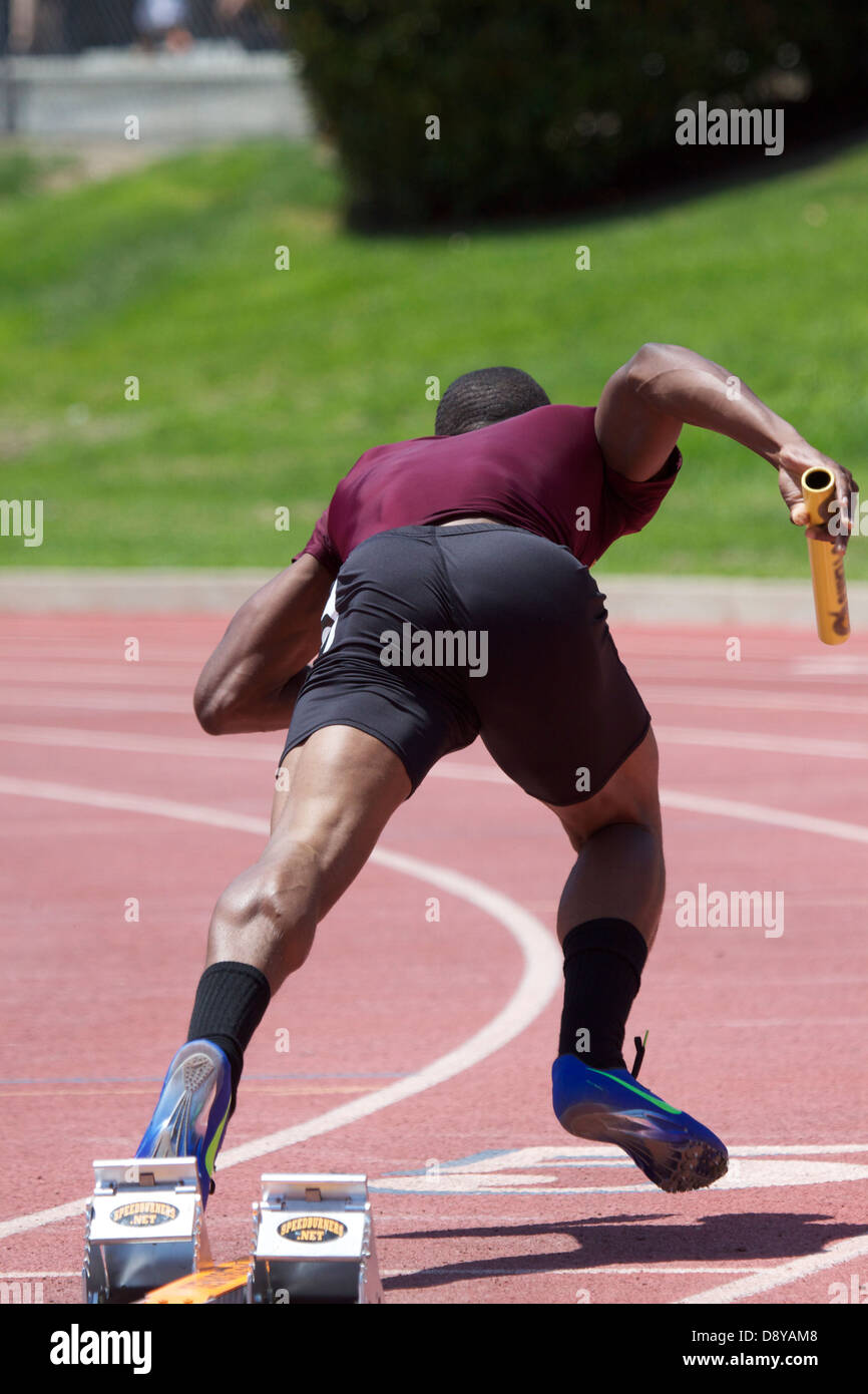 Relay runner leaving the starting clocks baton in hand Stock Photo