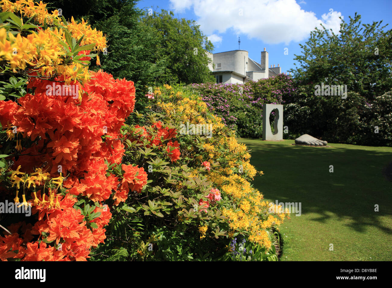 Colourful Azaleas in the grounds of the House for An Art Lover in Bellahouston Park, Glasgow with the Arch & Foot sculpture Stock Photo