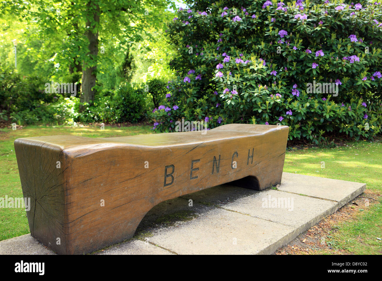 Wooden bench with the word bench carved into it in the gardens of the