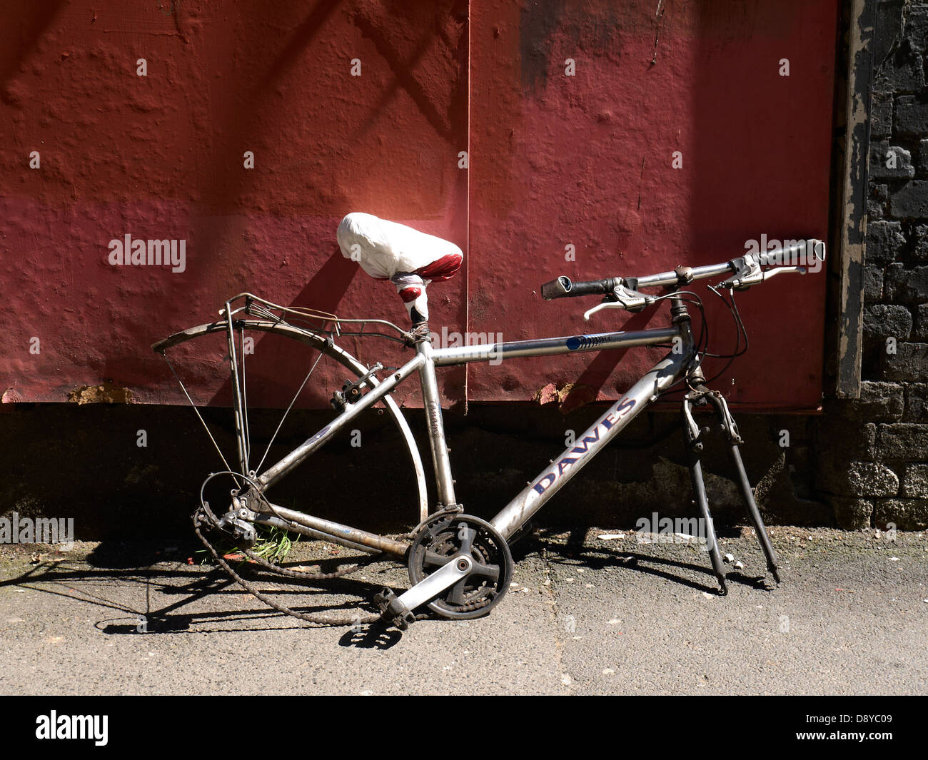 Remains of bicycle leaning against red wall Stock Photo