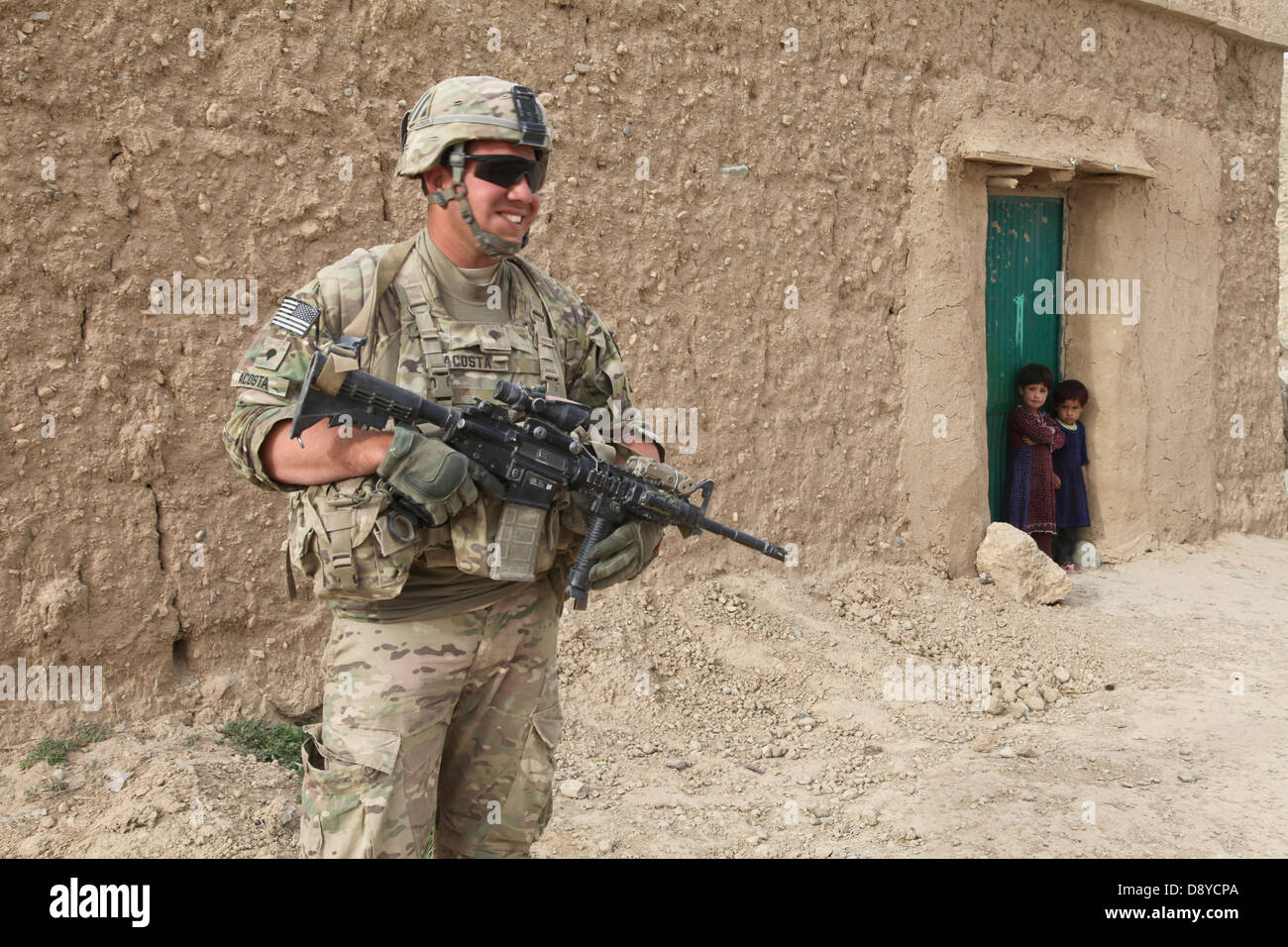 US Army Spc. Nate Acosta provides security during an operation near Forward Operating Base Shank as children watch May 25, 2013 in Logar province, Afghanistan. Stock Photo
