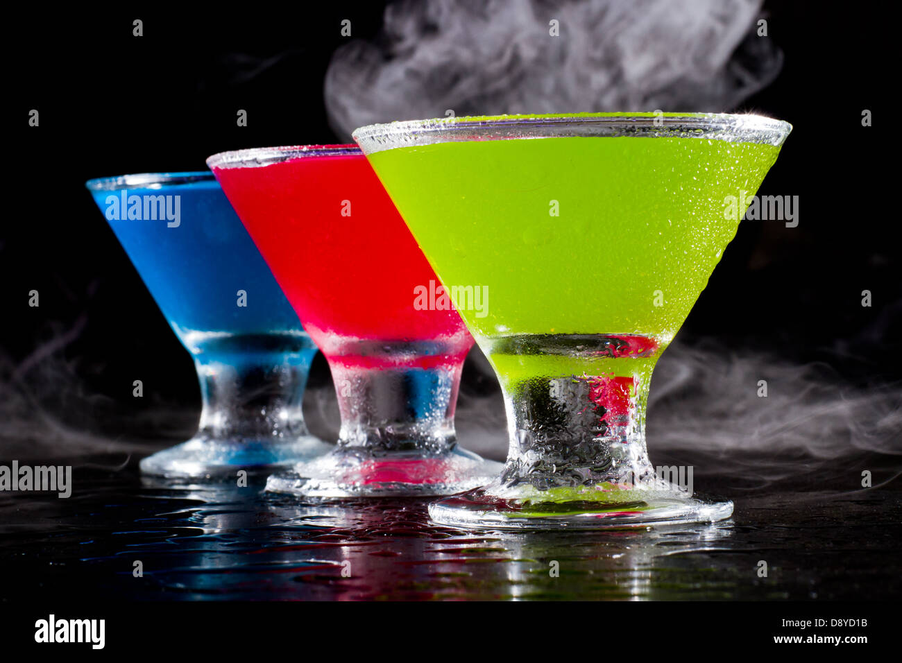 bright mini martinis served on a wet dark bar top with fog for a dramatic effect Stock Photo