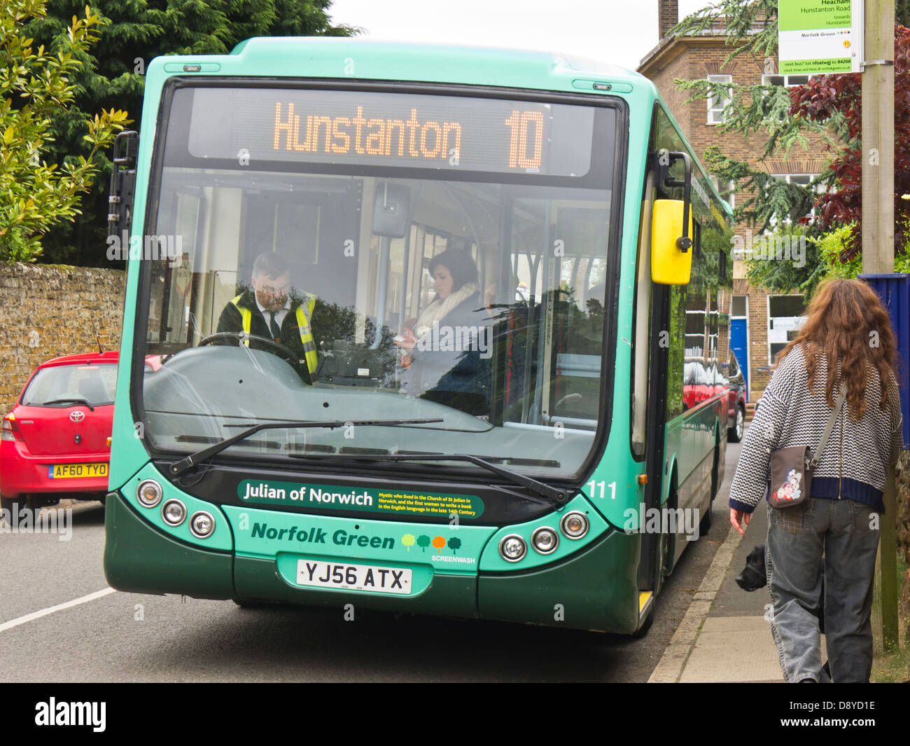 Woman boarding a rural bus in Heacham, Norfolk and paying the driver her fare. Stock Photo