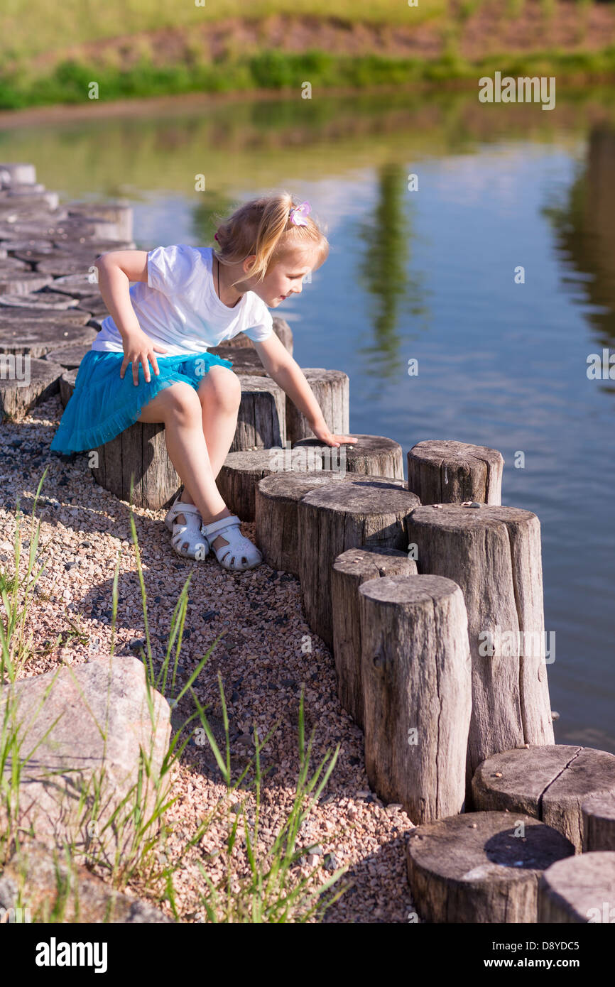 Cute little girl sitting near the lake in summertime in nature Stock ...