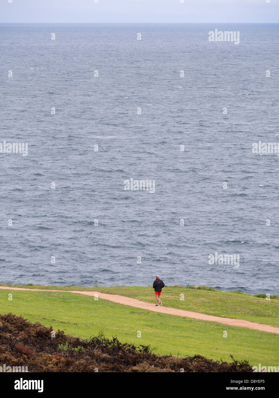 Man jogging alone next to the ocean Stock Photo