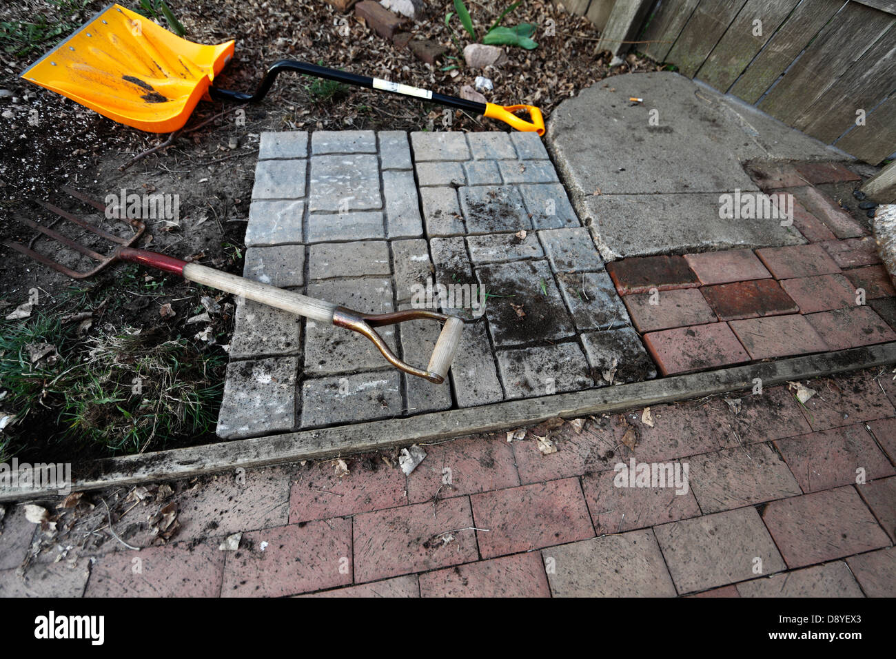 Patio under construction, showing square paver blocks next to older
