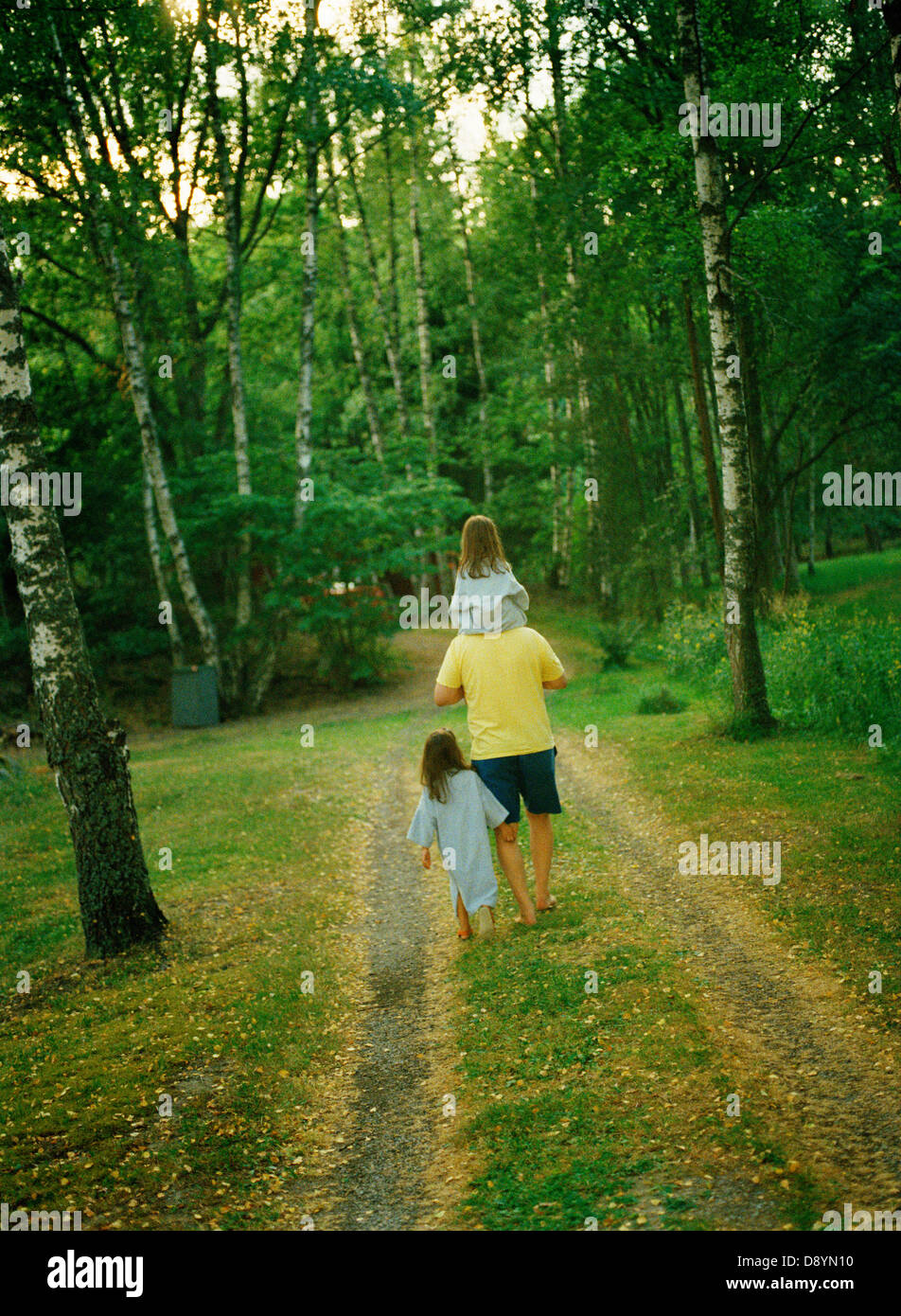 Father with two daughters walking in park Stock Photo - Alamy