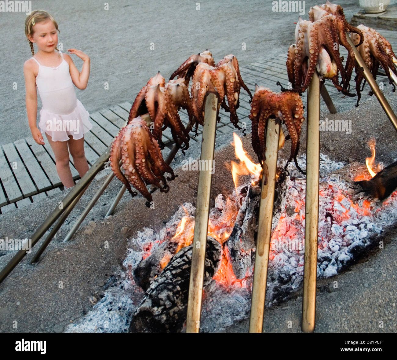 A girl standing by cuttle-fish being grilled. Stock Photo