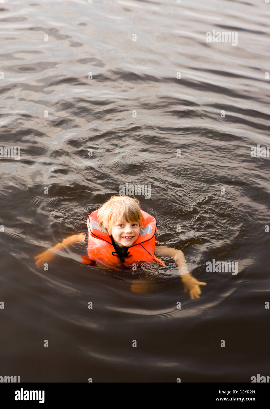 Boy wearing life jacket swimming in lake Stock Photo Alamy