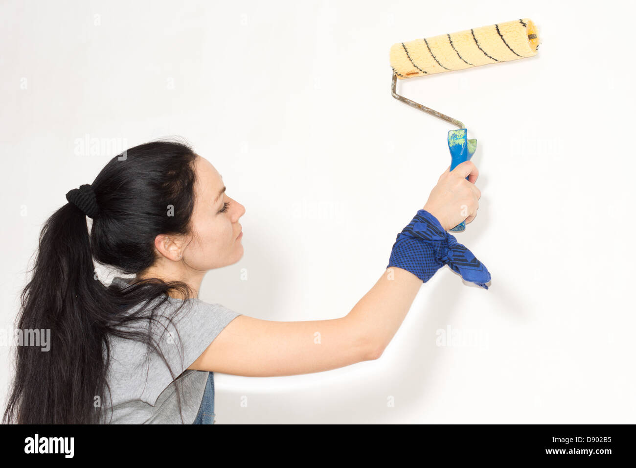 Woman painting a wall with a roller as she renovates or redecorates her home Stock Photo