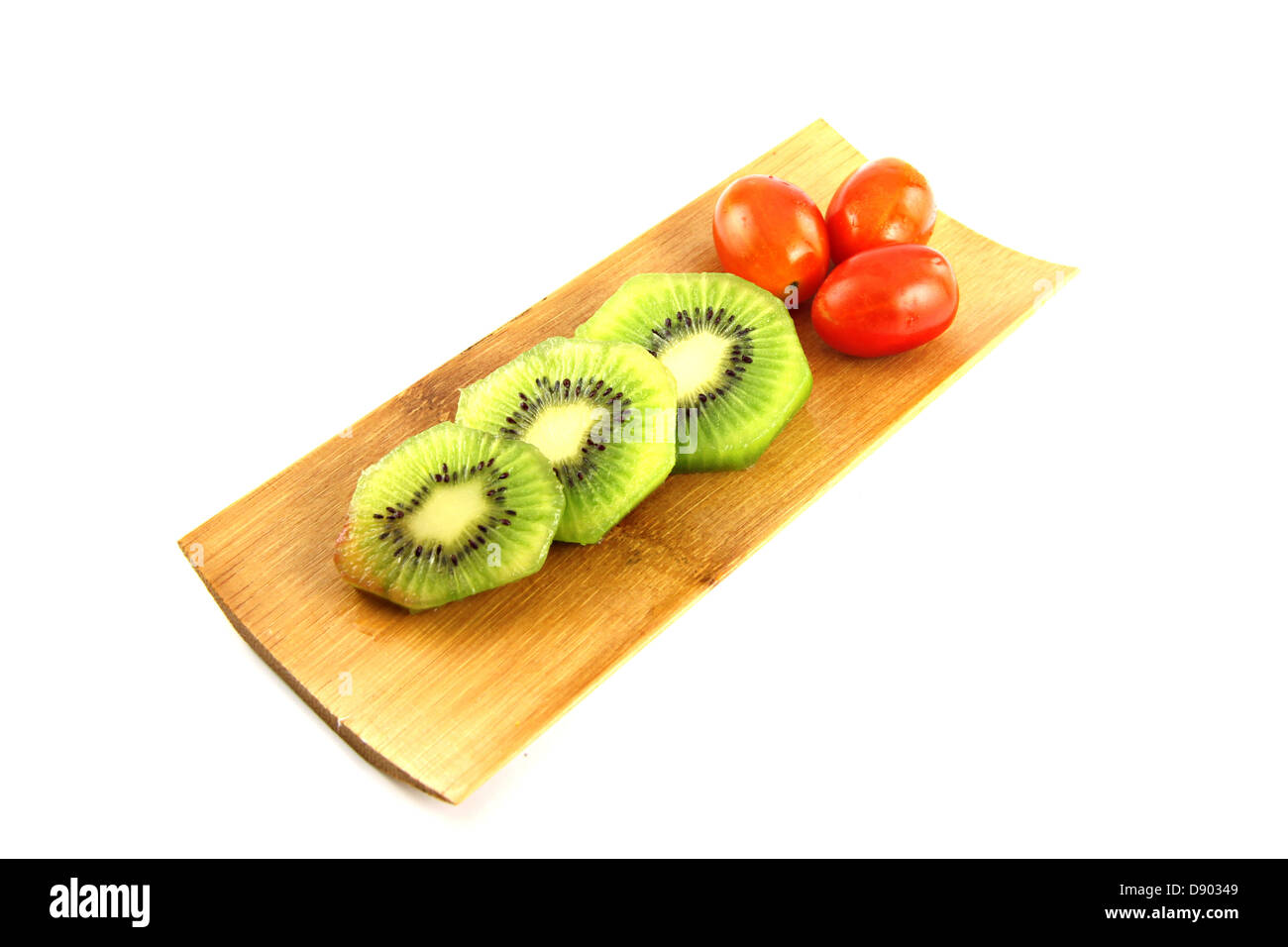 The Kiwifruit slices into pieces and three Tomato on the Bamboo dish. Stock Photo