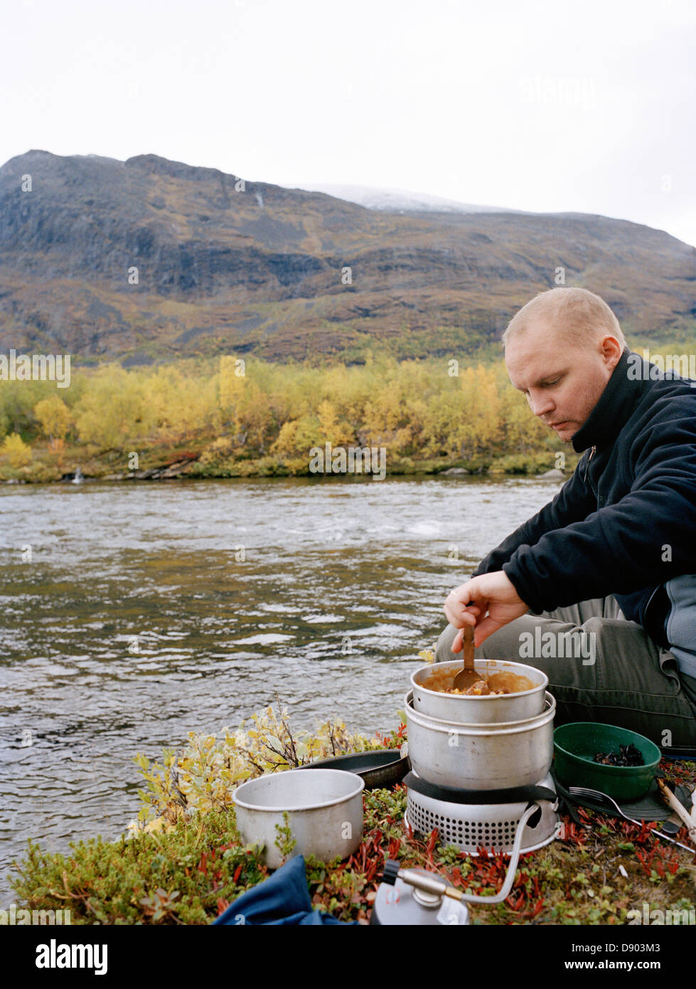 Man cooking while camping Stock Photo Alamy