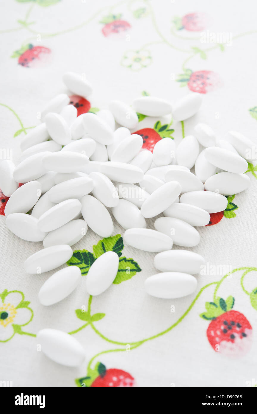 Heap of white pills on floral background Stock Photo
