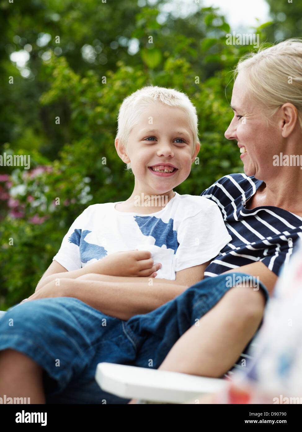 Mother and boy sitting in outdoor chair Stock Photo