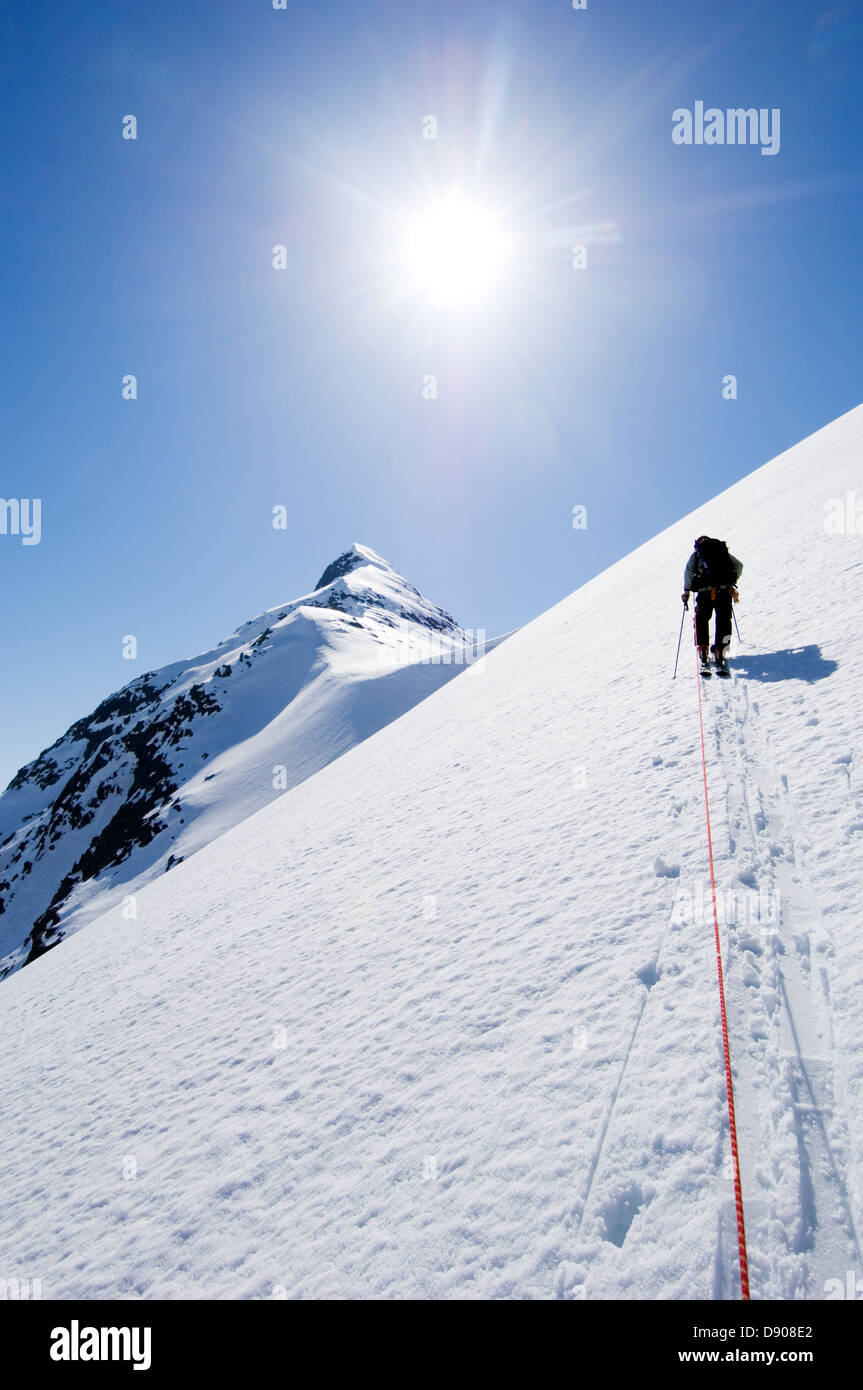 A skier climbing up a steep mountain side. Stock Photo