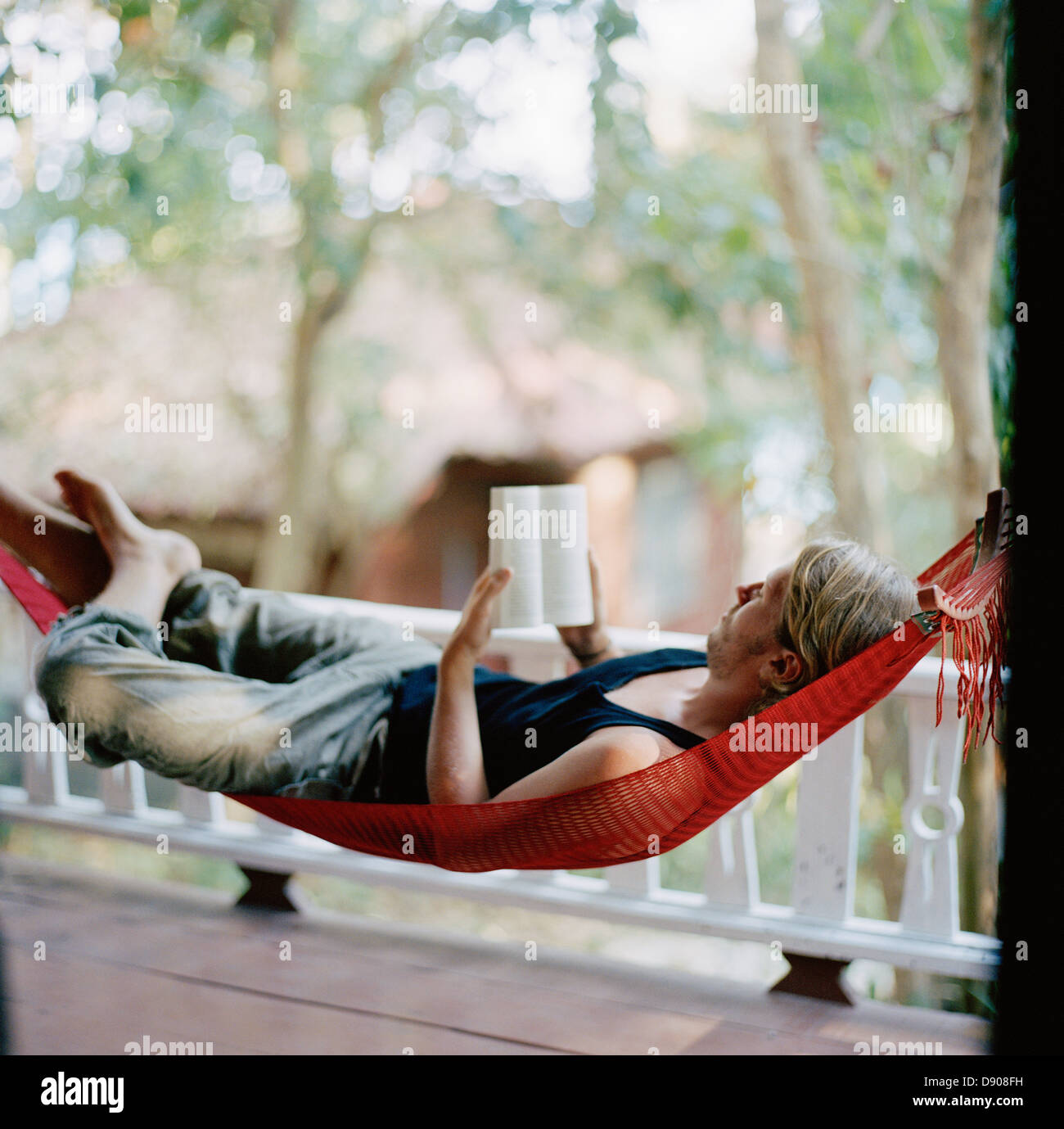 A young man in a hammock, reading a book, Thailand Stock Photo - Alamy