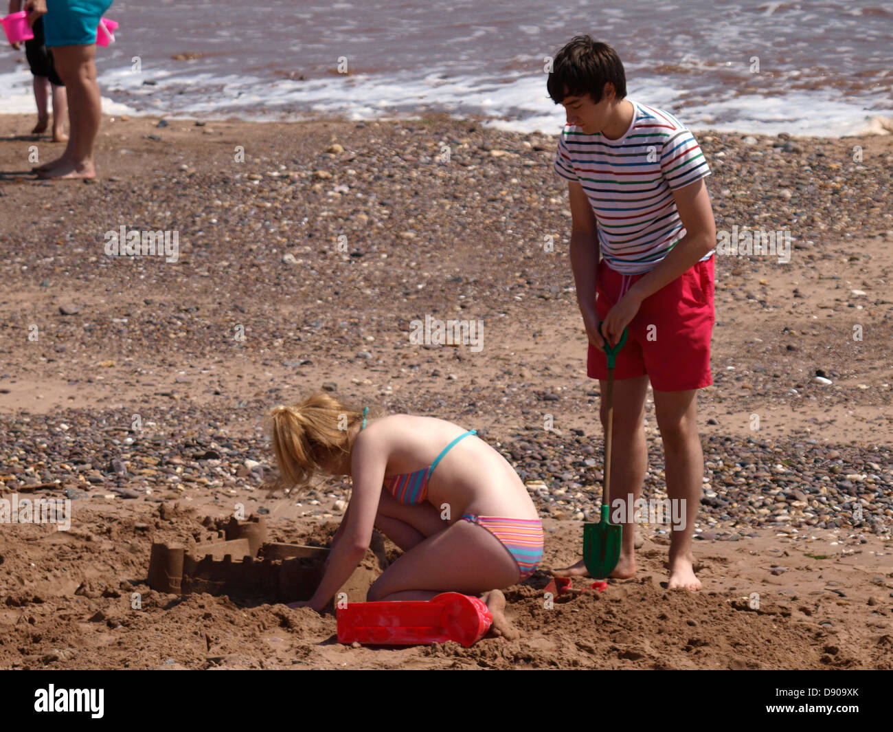 Teenagers build a sandcastle at the beach, UK 2013 Stock Photo