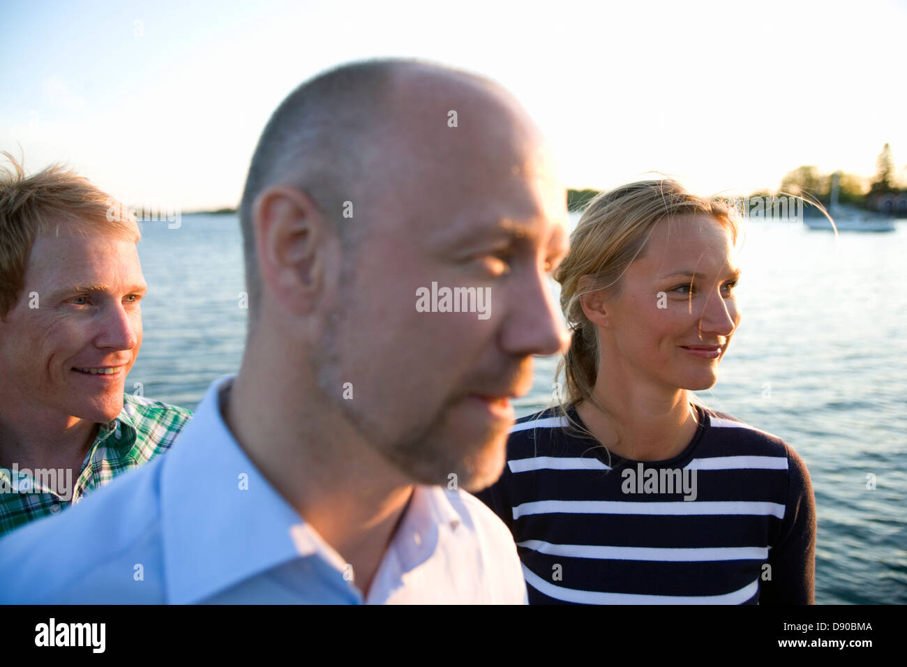 Three persons standing by the water, Fejan, Stockholm archipelago, Sweden. Stock Photo