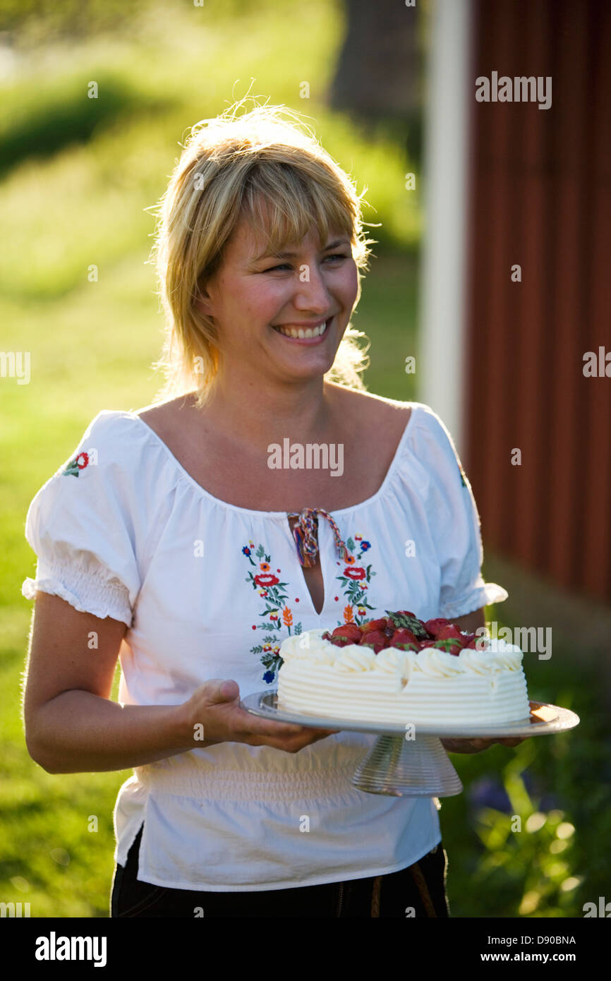 A woman and a strawberry cake, Fejan, Stockholm archipelago, Sweden. Stock Photo