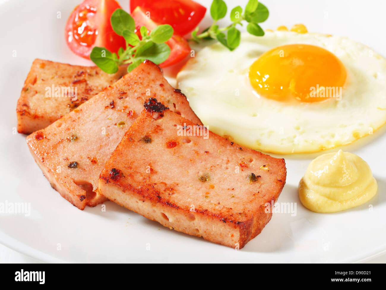 Panfried meatloaf with sunny side up fried egg and mustard Stock Photo