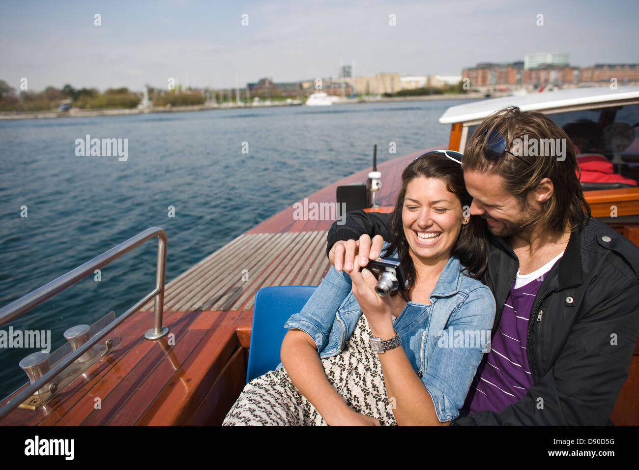Couple in boat looking at images in camera, smiling Stock Photo