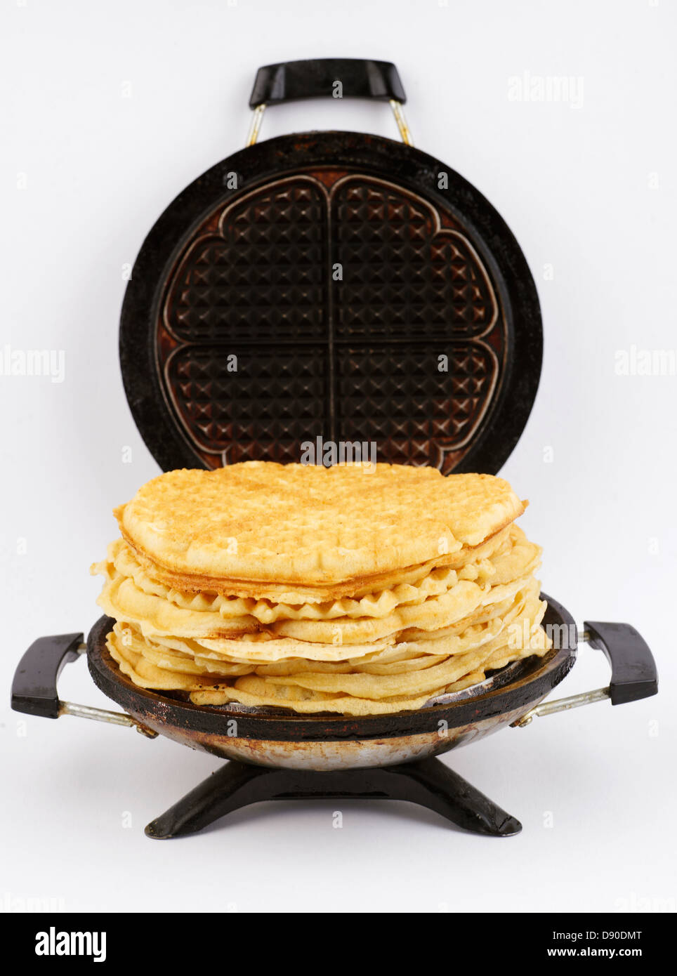 A waffle iron and a pile of waffles. Stock Photo