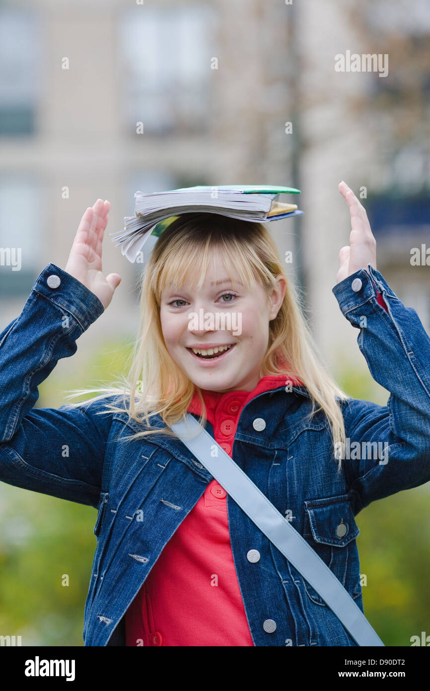 Portrait of smiling teenage girl holding books on head Stock Photo - Alamy