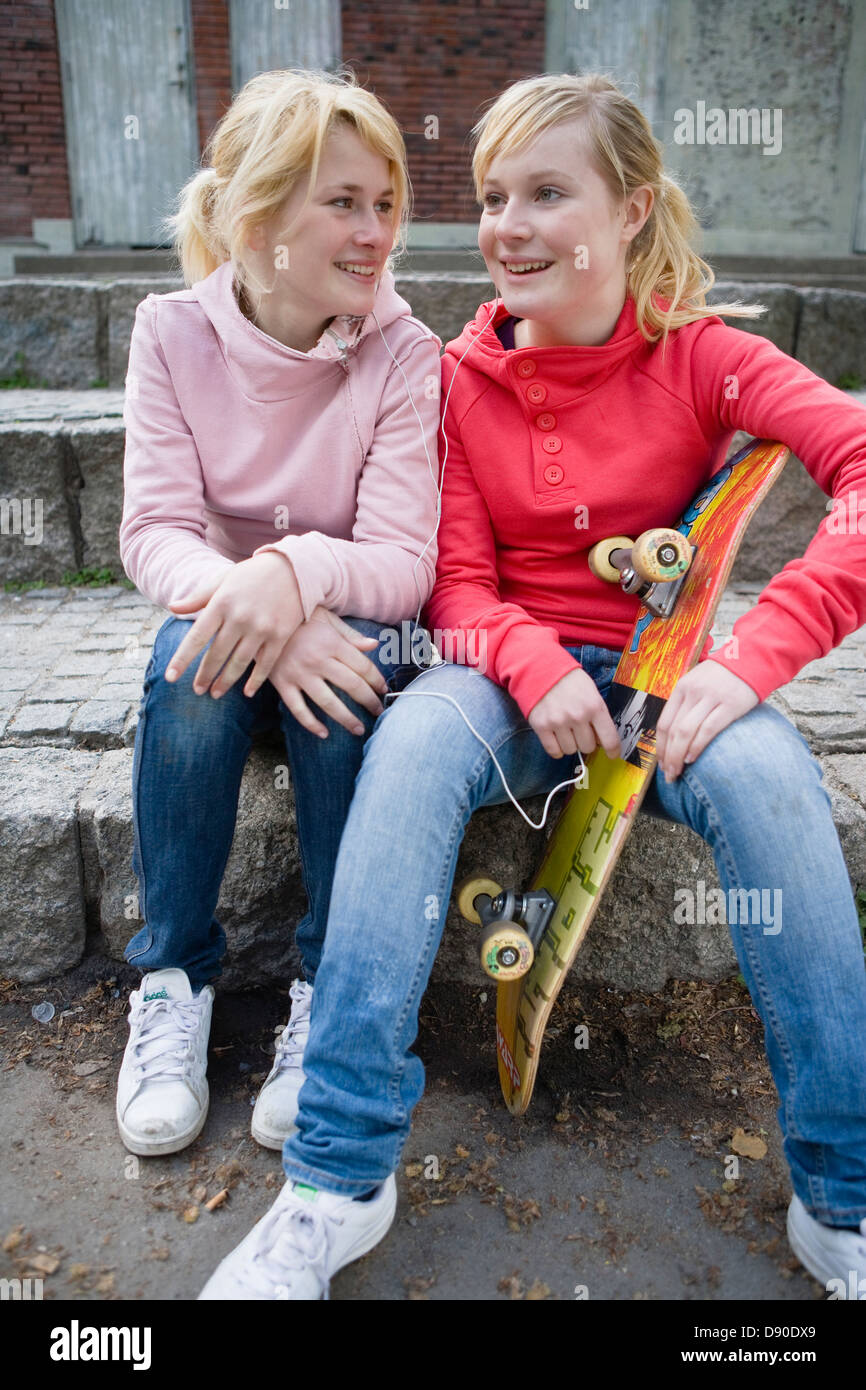 Two teen girls with skateboard sitting on curb Stock Photo - Alamy