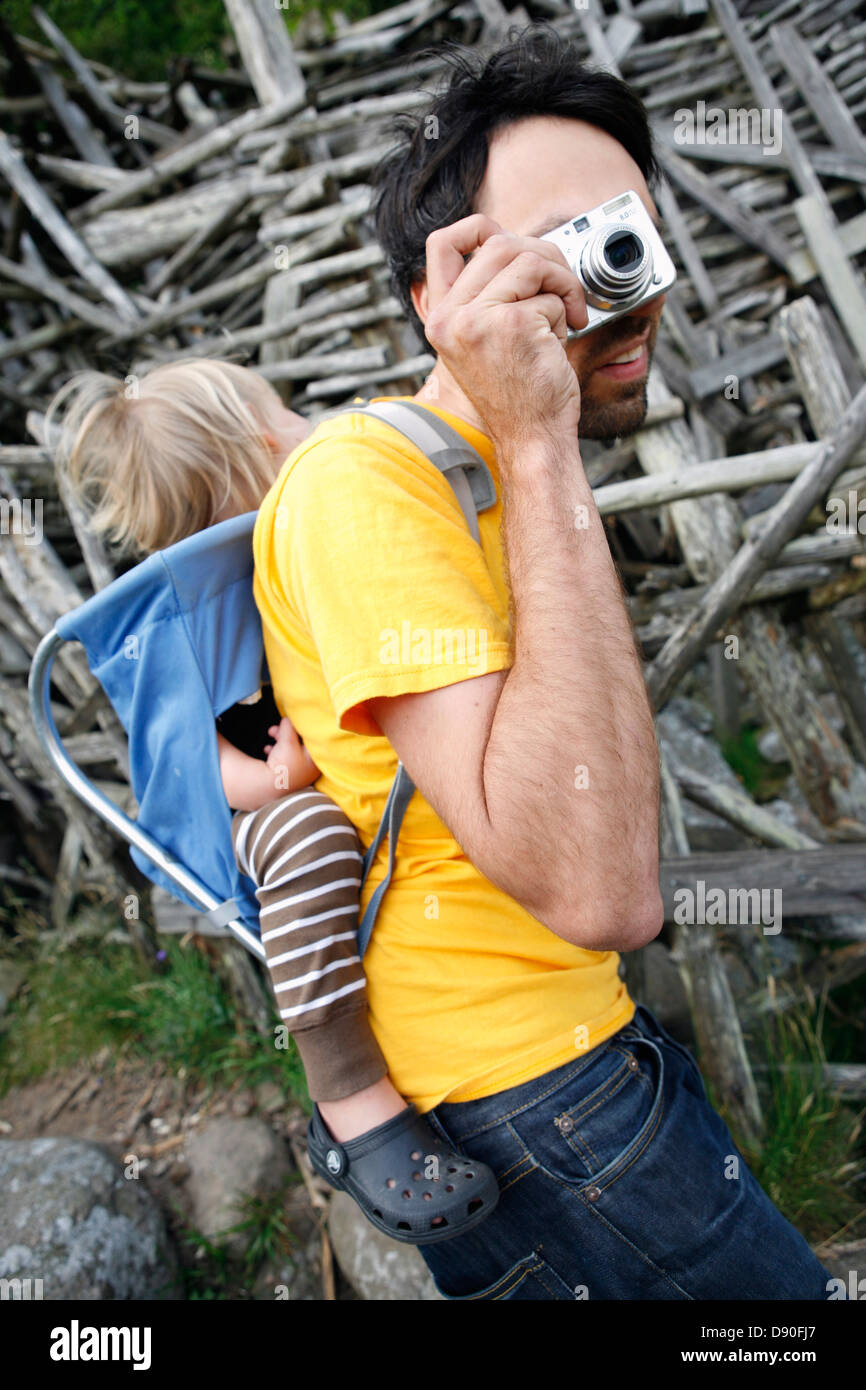 Father carrying daughter in baby carrier, photographing Stock Photo Alamy