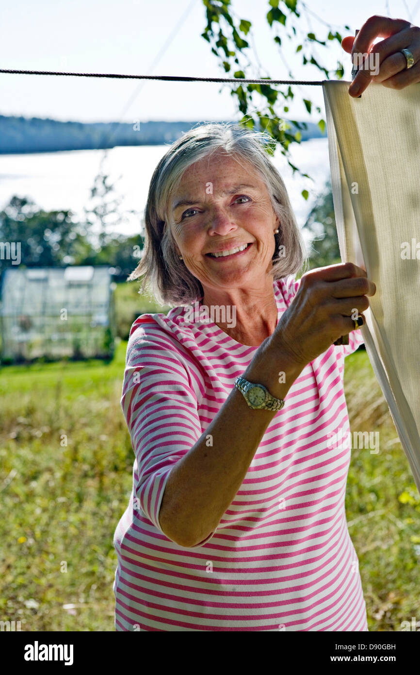 Woman hand washing and hanging up laundry outdoor in a sunny day. Woman  holding a tin bucket of water. Retro style Stock Photo - Alamy