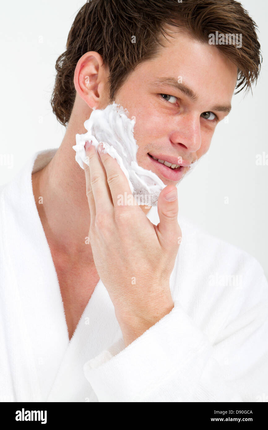 handsome young man apply shaving foam on face in bathroom Stock Photo