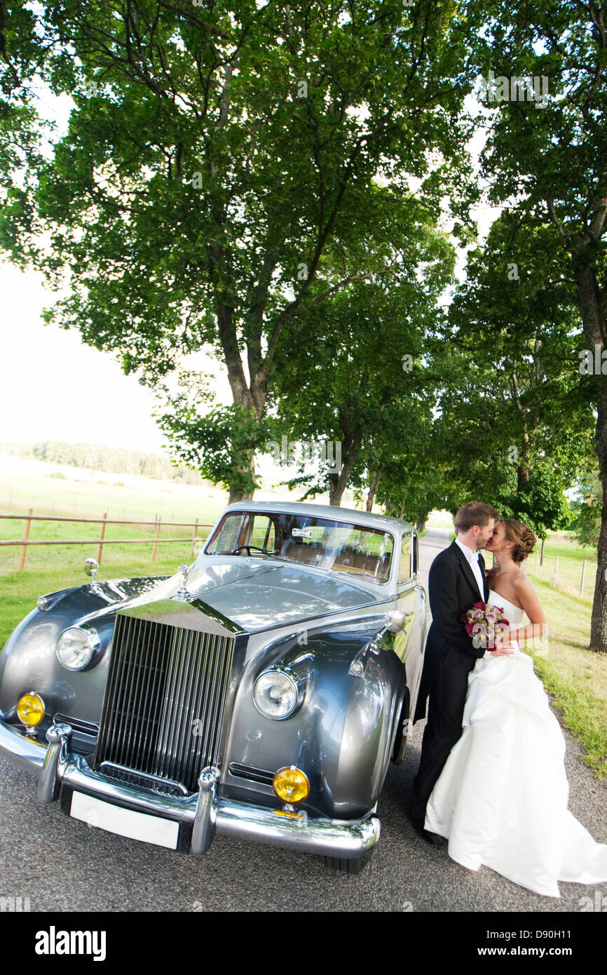 Bride and groom kissing by car Stock Photo