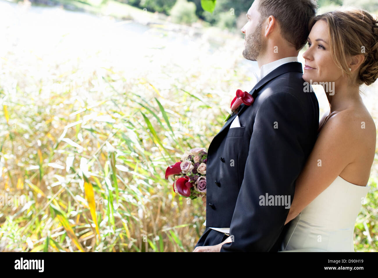 Bride and groom standing in field Stock Photo