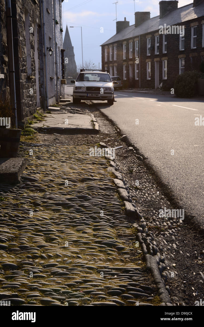 Stones laid in linear and herringbone patterns to form pavement and gutter outside a terrace of houses, Llanrhystud, Wales, UK. Stock Photo