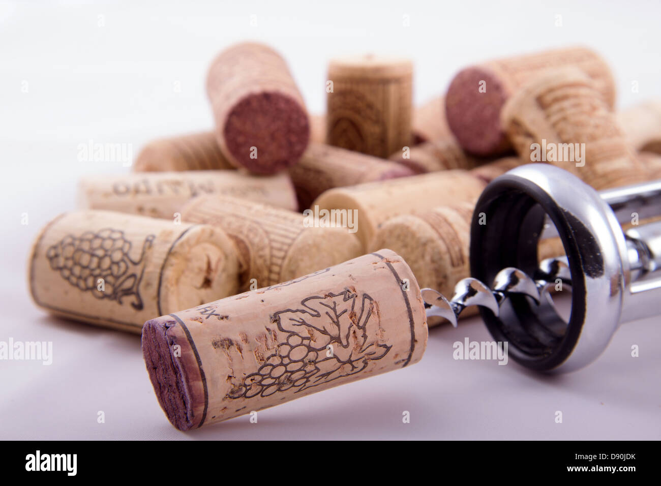 Bunch of corks with different designs and corkscrew in a white