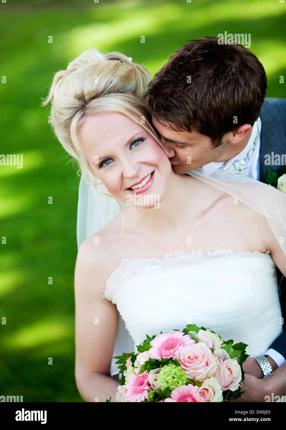 Groom embracing and kissing bride from behind Stock Photo
