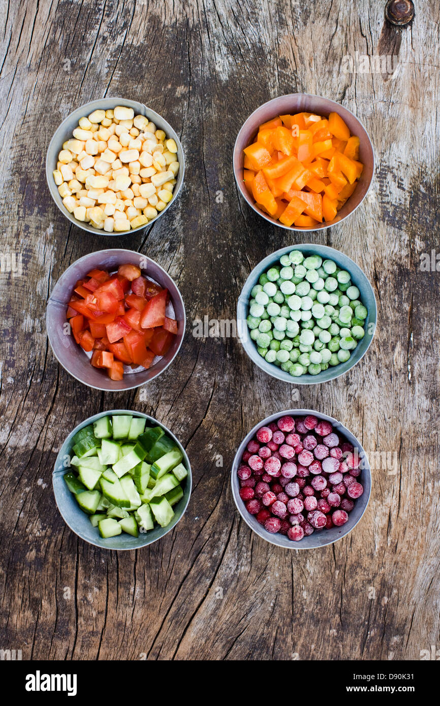 Chopped vegetables in bowls on hardwood floor Stock Photo