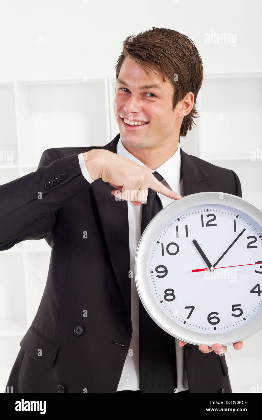 young businessman holding a clock in office Stock Photo Alamy