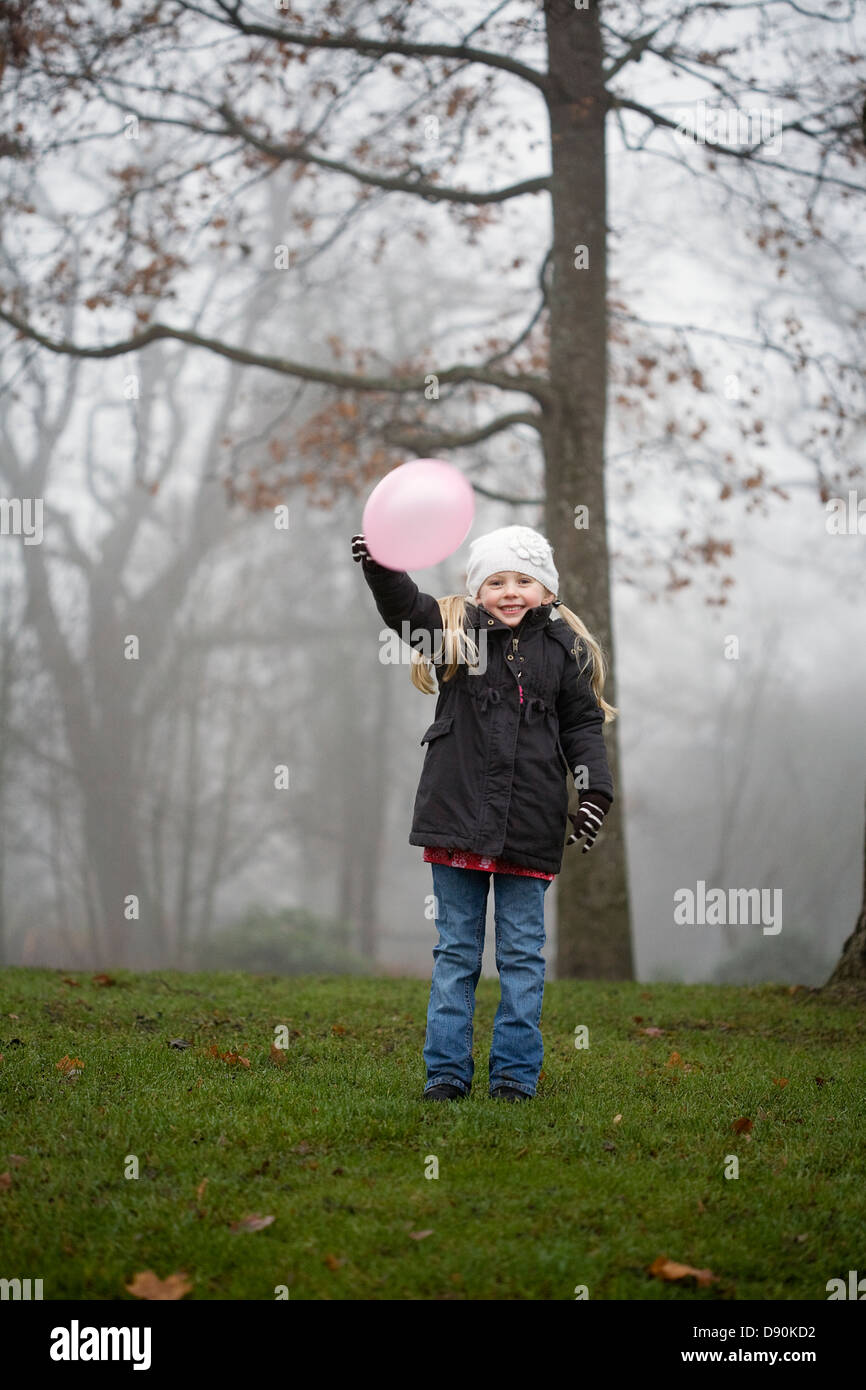 Outdoor portrait of girl wearing warm clothing, holding balloon Stock Photo
