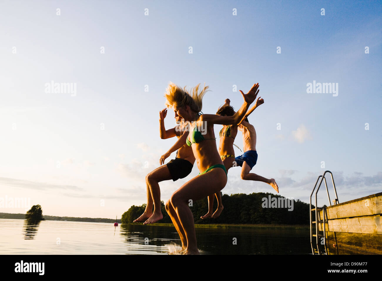 Friends jumping into lake Stock Photo - Alamy