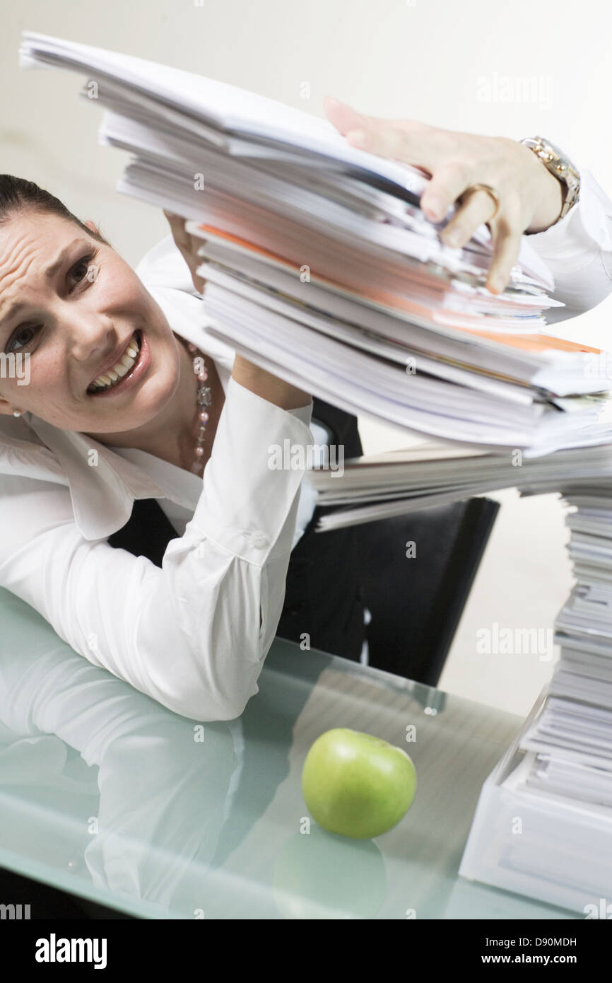 A woman in an office with a large pile of paper. Stock Photo