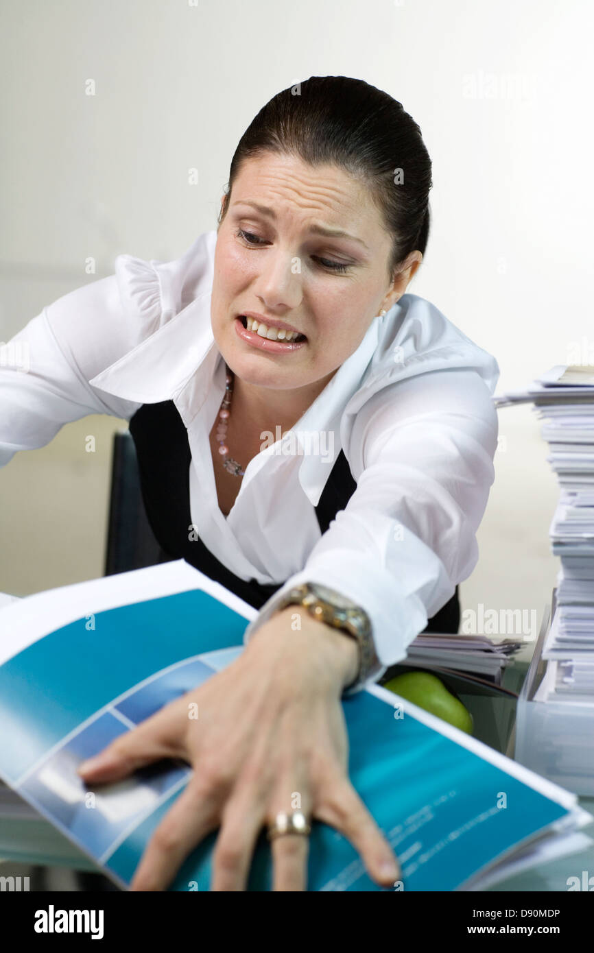 A woman in an office with a large pile of paper. Stock Photo