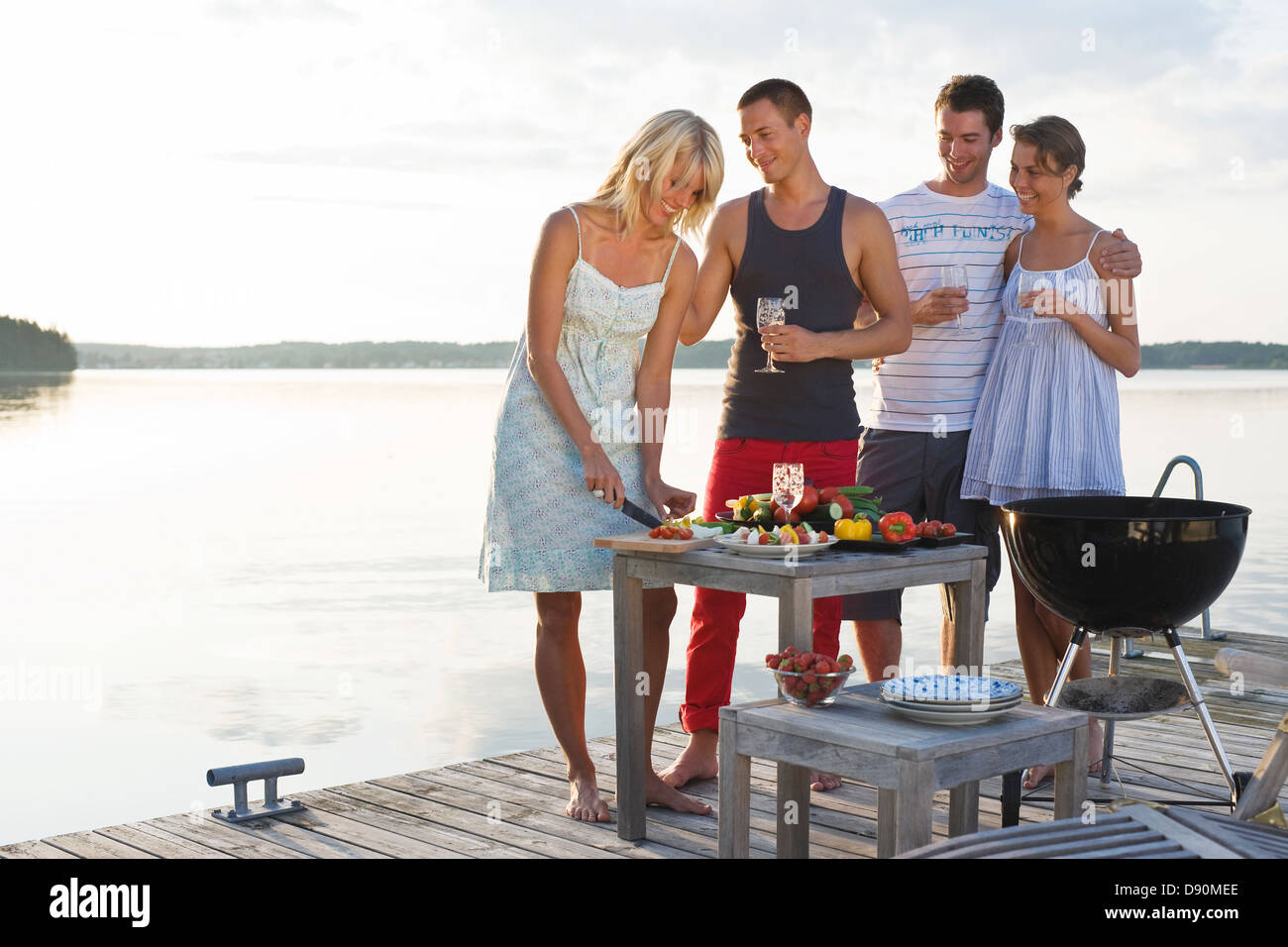 Four people on jetty cooking meal Stock Photo - Alamy