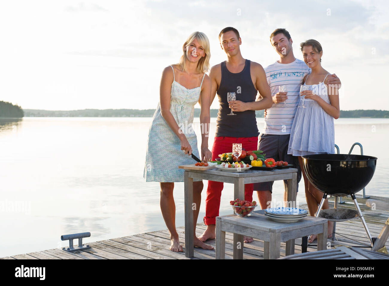 Four people on jetty cooking meal Stock Photo - Alamy