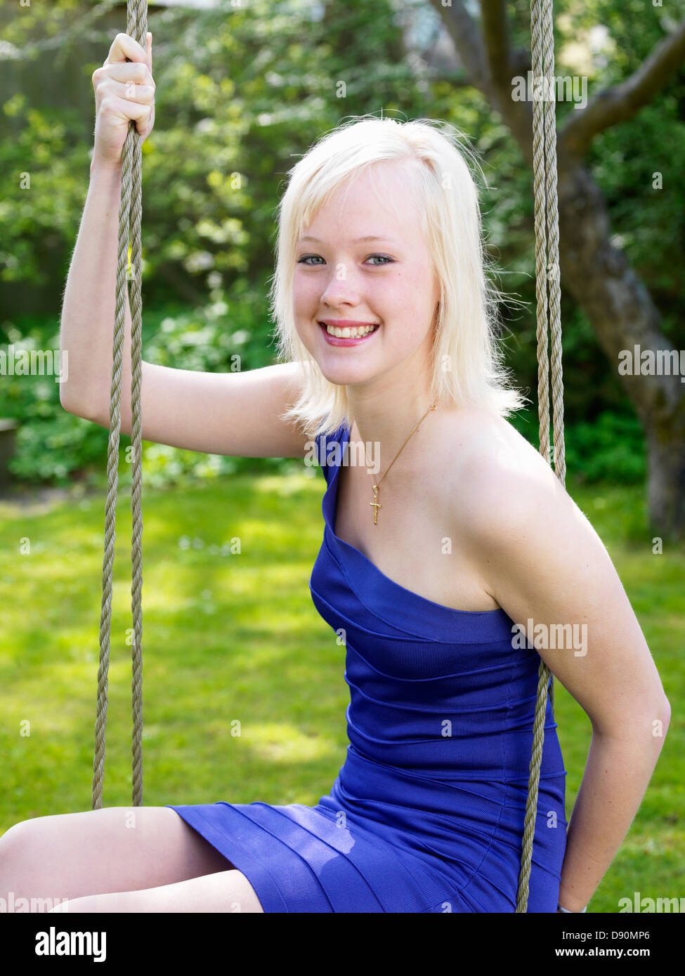 Girl in blue dress sitting on swing Stock Photo - Alamy
