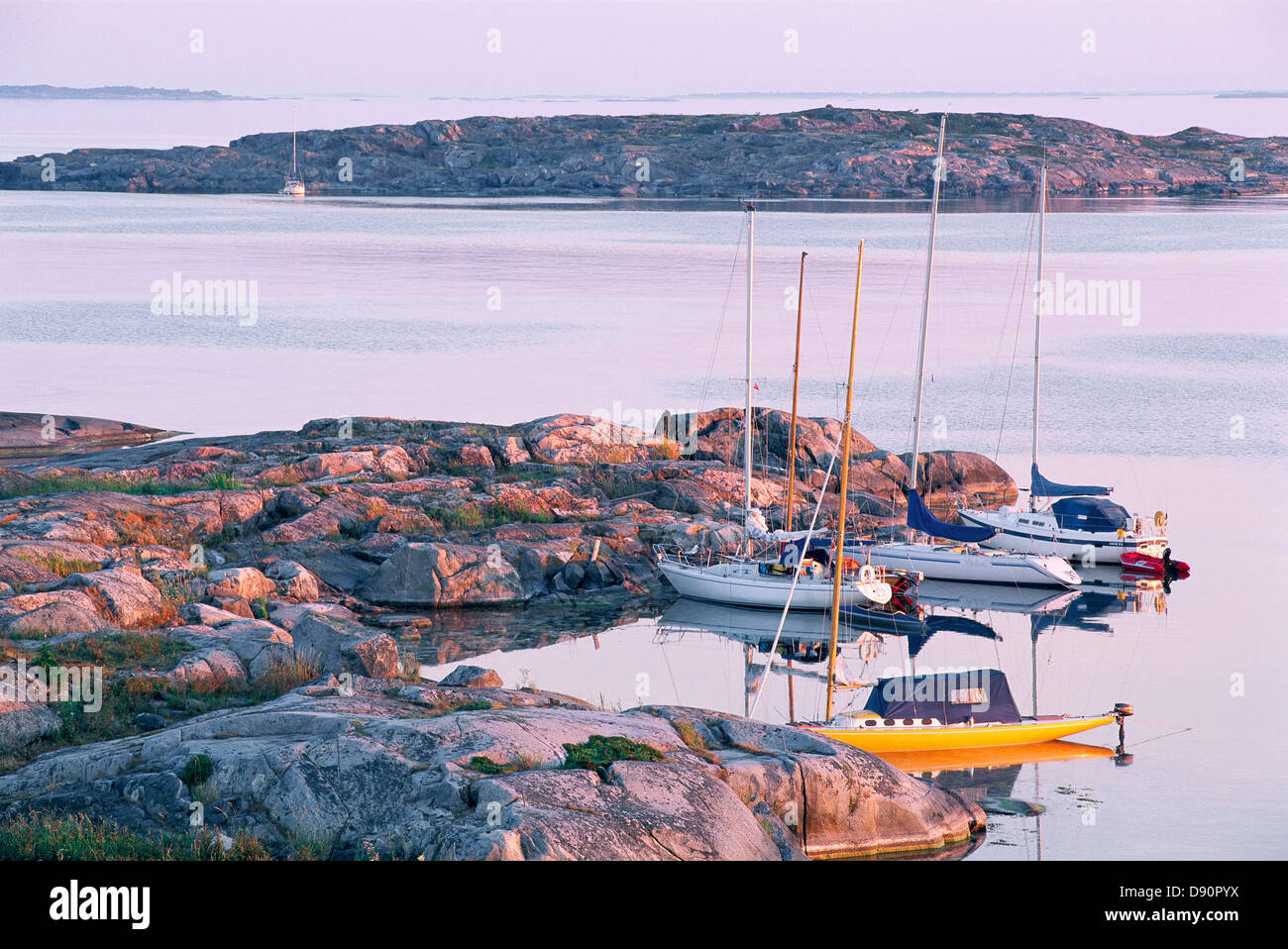 Boats anchored on rocks by sea Stock Photo - Alamy
