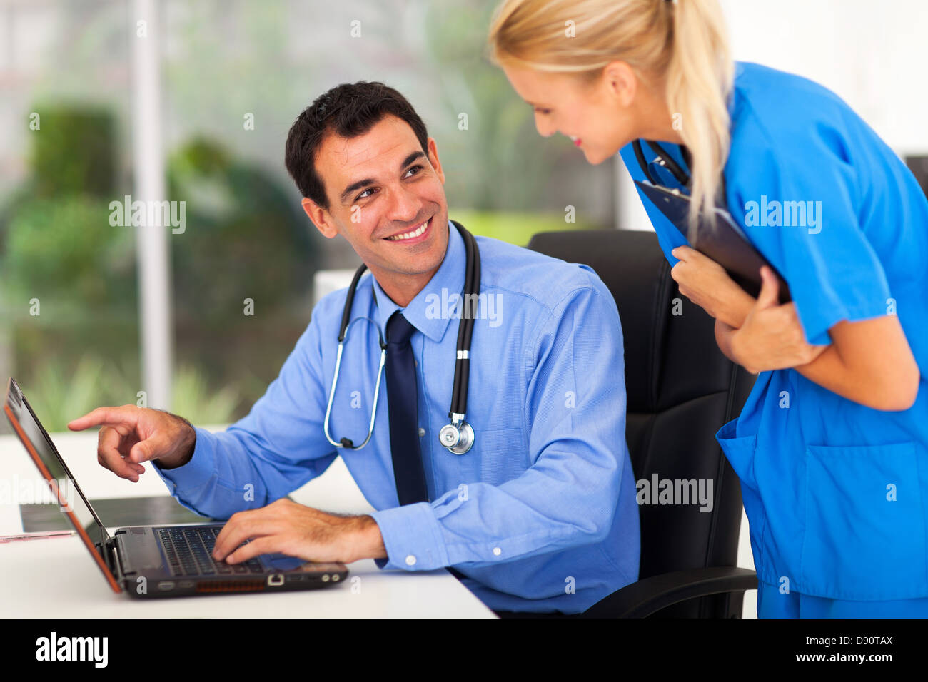 cheerful male doctror discussing work with assistant in office Stock Photo