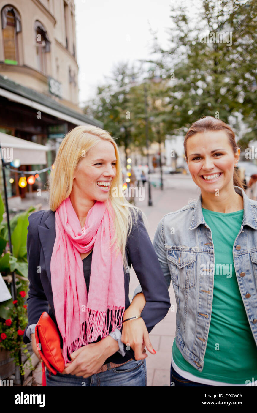 Two women walking arm in arm on pavement Stock Photo Alamy
