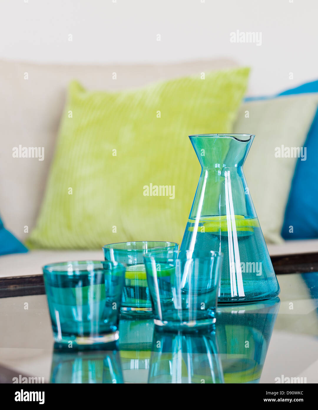 Decanter with glasses, sofa in background Stock Photo