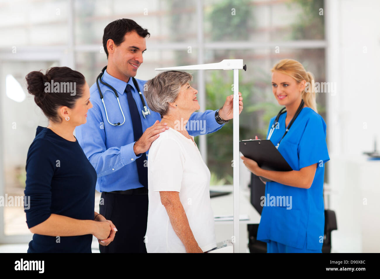 general practitioner measuring senior patient's height in office Stock Photo